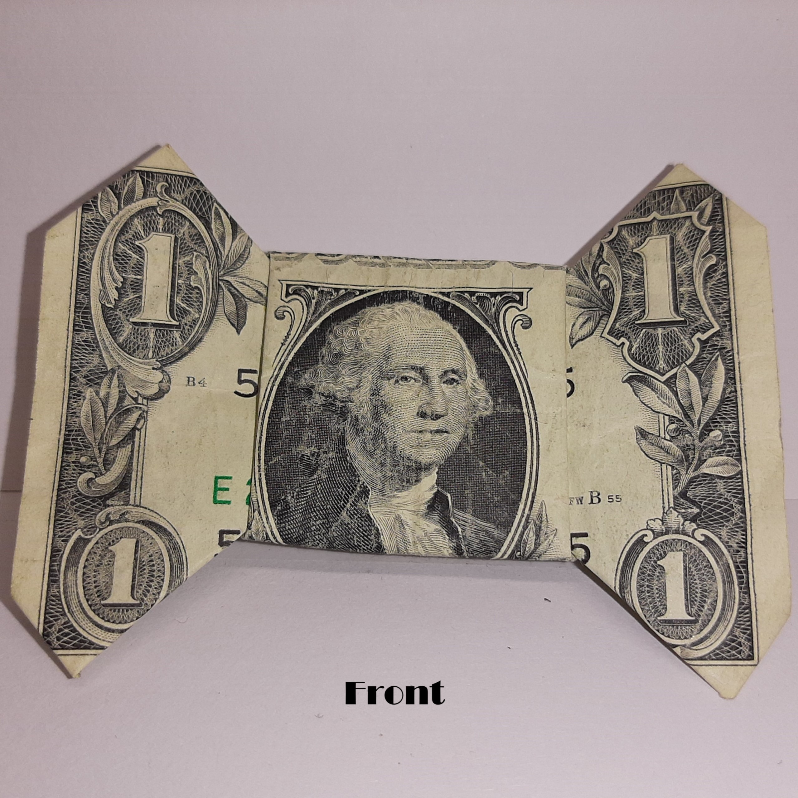 A 1 dollar bill folded to be a bow with George Washington facing front.